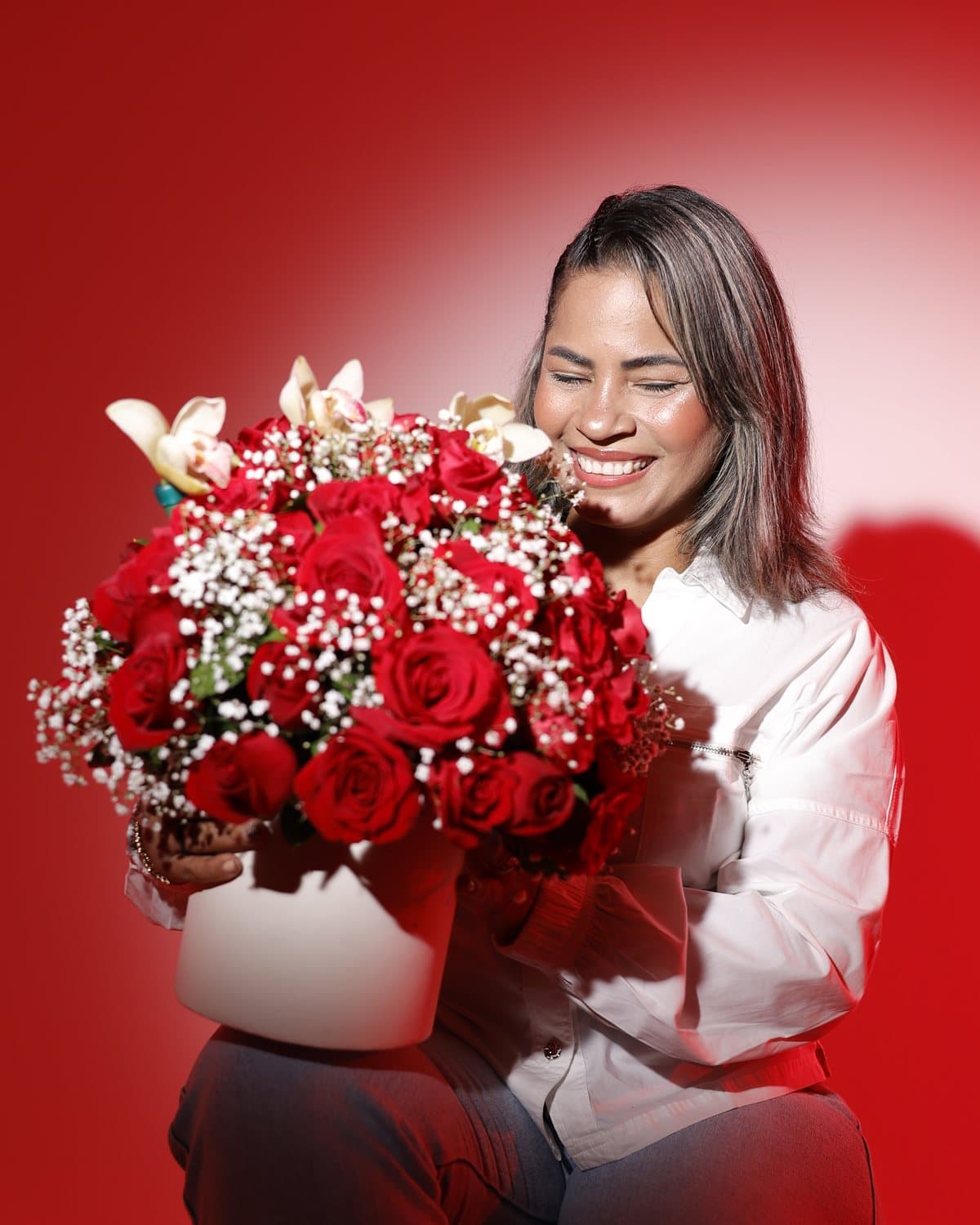 Irma Calderón sonriendo con un arreglo de rosas rojas en las manos