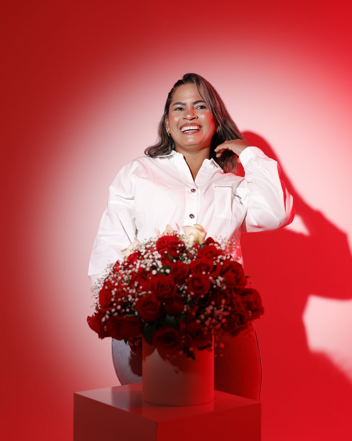 Irma Calderón sonriendo junto a un arreglo de rosas rojas